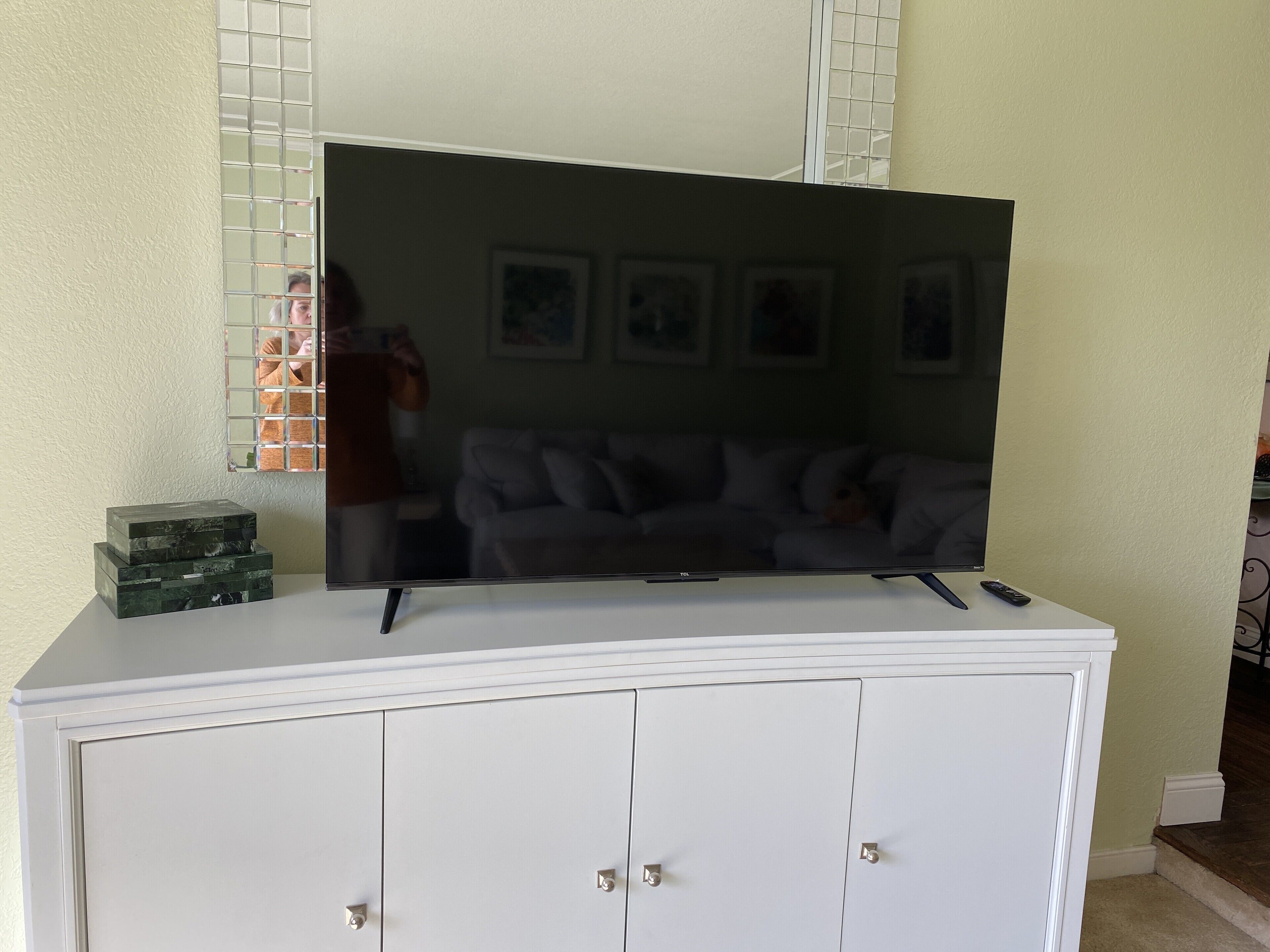 Un téléviseur à écran plat posé sur un meuble blanc, avec une télécommande à côté.