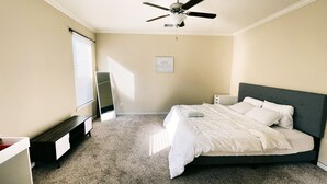 A bedroom with a bed, a ceiling fan, a bedside table, a dresser, and a mirror. - Spacious, New build 4 bedroom house in Conroe (Conroe)