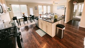 A modern kitchen with a central island, a dining area with chairs, and a view of a living room. - Spacious, New build 4 bedroom house in Conroe (Conroe)