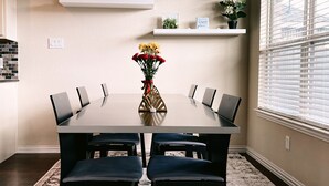 A conference room with a rectangular table, six chairs, a vase with flowers, and shelves with plants and decorative items. - Spacious, New build 4 bedroom house in Conroe (Conroe)