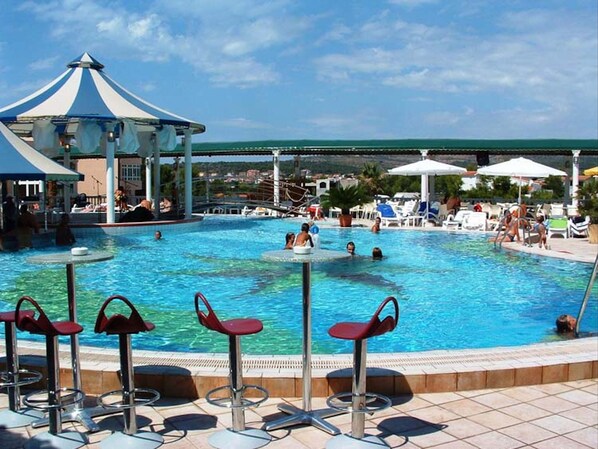 Relax by the pool surrounded by a lounge area and a gazebo.