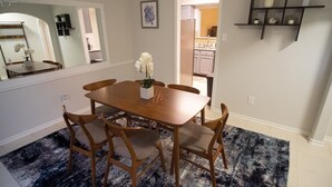 A dining area with a wooden table and chairs, a black and white patterned rug, and a kitchen visible through an open doorway. - Cozy and Spacious 3 Bedroom Home in Sugarland (Sugar Land)