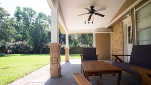 A covered patio area with a table and two chairs, a stone pillar, and a ceiling fan. - Cozy and Spacious 3 Bedroom Home in Sugarland (Sugar Land)