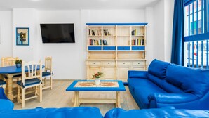 A modern living room with a blue sofa, a wooden coffee table, and a bookshelf.