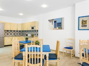 Une cuisine compacte avec des meubles en bois, un four à micro-ondes et un dosseret de carreaux bleus.