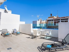 Une terrasse sur le toit avec des sièges extérieurs, une piscine et une vue dégagée sur les toits de la ville.
