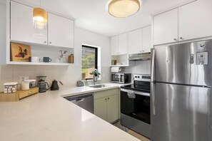 Eine moderne Küche mit Edelstahlgeräten, weißen Schränken und einem Fenster für natürliches Licht.