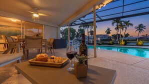 Ein Poolbereich mit Tisch, Stühlen, einer Weinflasche und einer Auswahl an Gebäck.