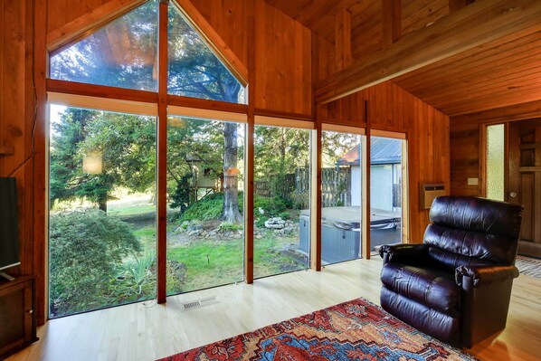 Una habitación con ventanas amplias, un sillón de cuero y una alfombra estampada.