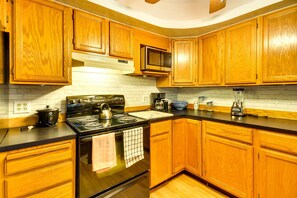Una cocina con armarios de madera, una estufa negra, un microondas y una cafetera.