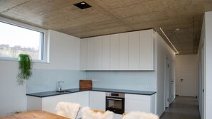 Une cuisine moderne avec des meubles blancs, un plan de travail noir et une table à manger en bois, assortie de chaises blanches.