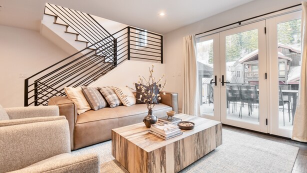 A modern living room with a sofa, coffee table, and a staircase with a railing.