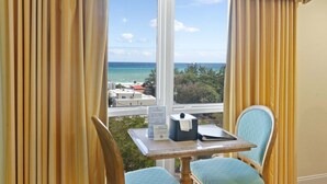 Une pièce avec vue sur l’océan, une table avec un carnet et une chaise.