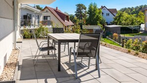 Un patio con mesa y sillas, vistas de casas vecinas y un cielo despejado.