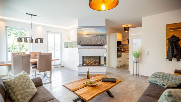 Una sala de estar moderna con chimenea, un comedor y una cocina a la vista.