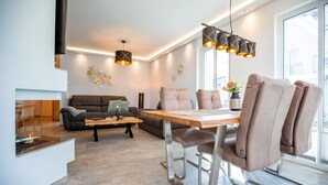 Una sala de estar moderna con comedor, un sofá, una mesa de centro e iluminación colgante.