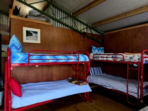 Une chambre avec des lits superposés, des murs en bois et un escalier en métal.