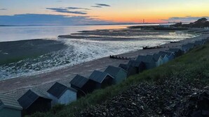 Udsigt over kysten med en række strandhuse langs stranden.