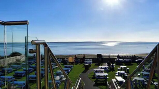 A view from a high vantage point overlooking a parking lot with rows of cars, a grassy area, and a body of water in the distance. - Seaview dog friendly ground floor flat 1 min to beach sleeps 4 (Fareham)