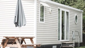 A mobile home with a sliding door, a small porch, and a picnic table. - Woodland Chalet in the Ardennes (Olloy-sur-Viroin)