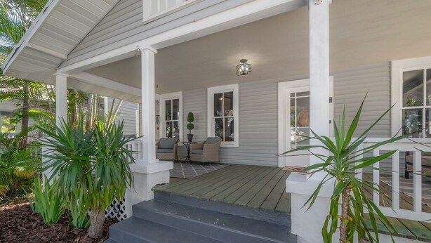 A covered porch with a set of stairs leading up to a seating area with a table and chairs.