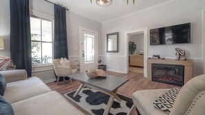 A living room with a sofa, a coffee table, a fireplace, and a TV mounted on the wall.