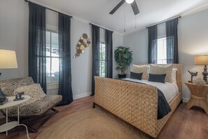 Une chambre avec un grand lit, un canapé, une petite table et un ventilateur de plafond.