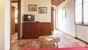 A cozy room with a wooden cabinet, a television, and a wicker table with magazines.