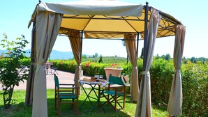 Een overdekt terras met een tafel voor twee personen, omringd door groen en een mooi uitzicht.