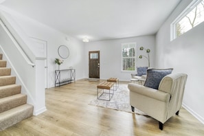 A spacious living area with a staircase, a sofa, a coffee table, and a rug.