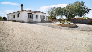 Un bâtiment blanc avec un toit en tuiles, une cheminée et une allée gravillonnée.