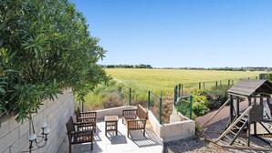 Une terrasse avec des meubles d’extérieur, une structure en bois et une vue sur un champ.