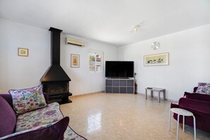 Una sala de estar con chimenea, televisión de pantalla plana y sofá.