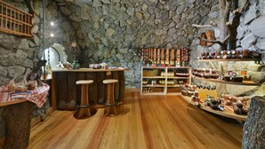 Un interior rústico con pared de piedra, taburetes de madera y estantes llenos de frascos.