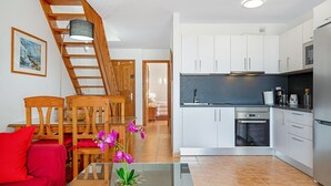 Una cocina moderna con armarios blancos, horno empotrado y refrigerador de acero inoxidable.