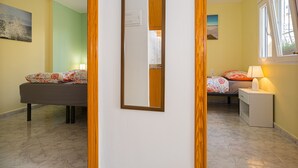 A bedroom with a bed, bedside table, lamp, and a mirror.