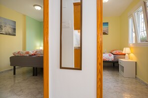 A bedroom with a bed, bedside table, lamp, and a mirror.