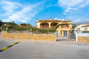 A two-story house with a stone wall, a balcony, and a gate.