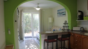 A kitchen with a green archway, a ceiling fan, a coffee maker, and a bar area with two stools.