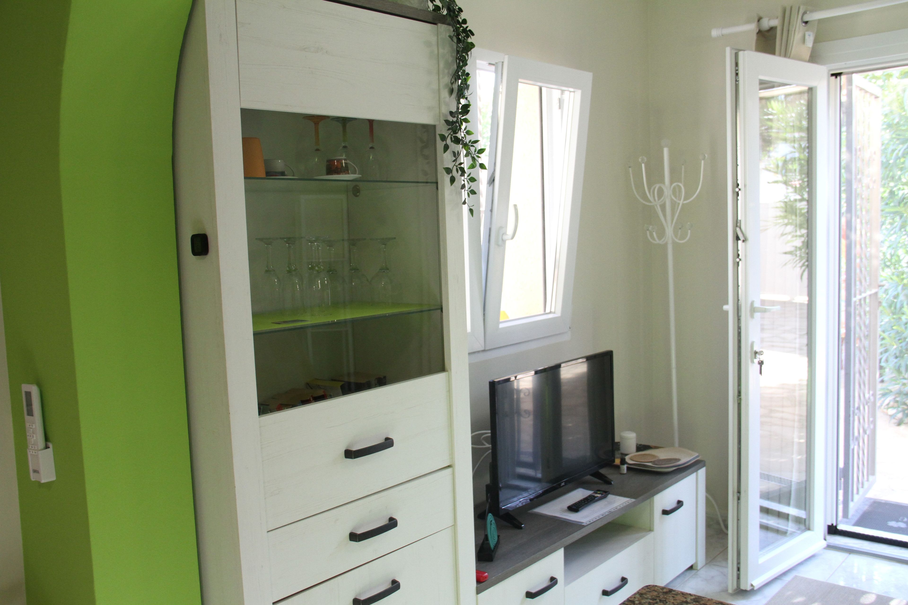 A room with a white cabinet, a television, and a glass door leading outside.