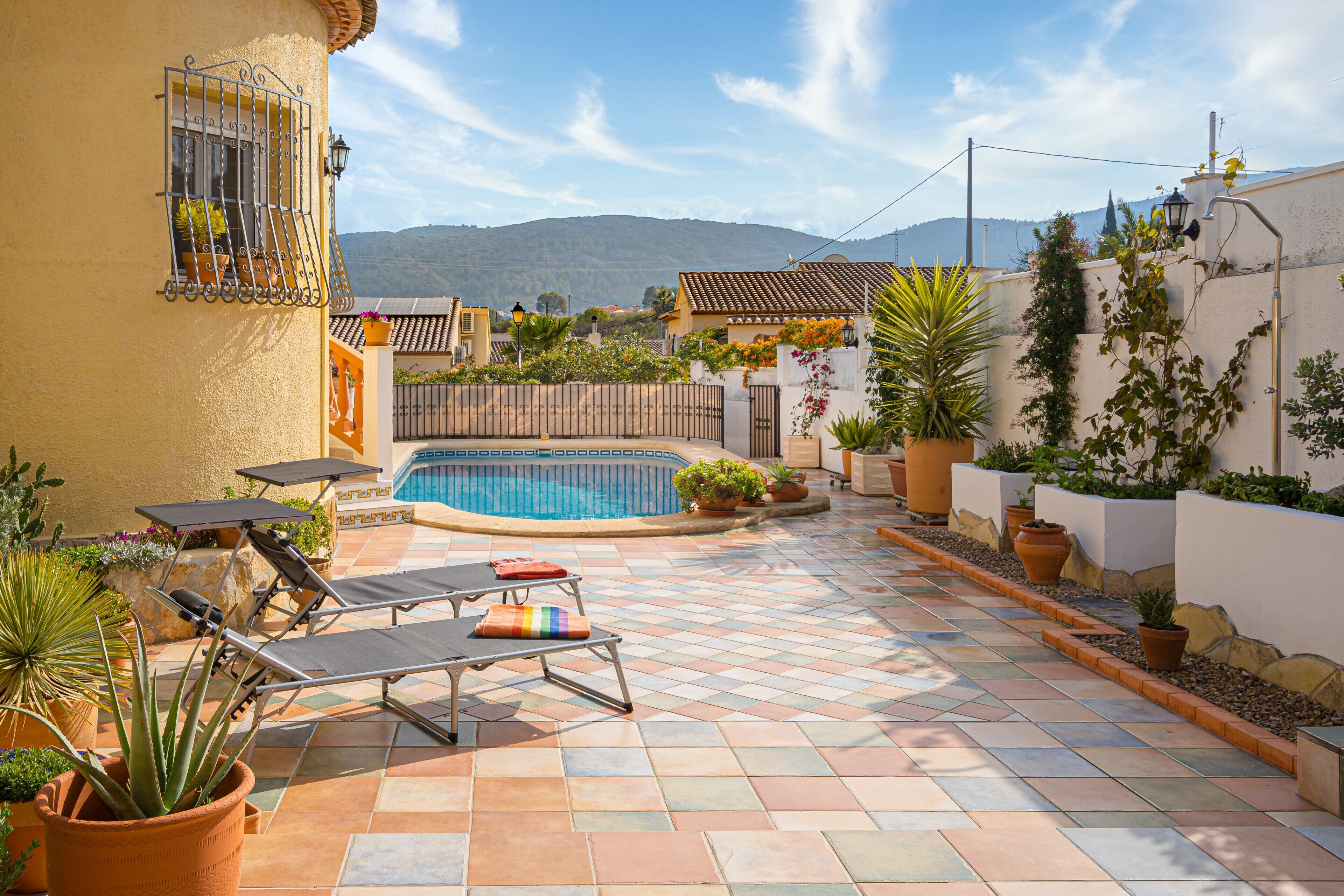 Un área junto a la piscina con sillones de descanso, una piscina pequeña y plantas en macetas.