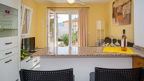 A kitchen with a granite countertop, white cabinets, a ceiling fan, and a dining area with two chairs. - Apartment "La Mandarina" with Mountain View, Pool, Wi-Fi, A/C & Terrace (Palmeria)
