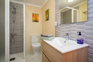 A bathroom with a shower, toilet, sink, and a mirror.