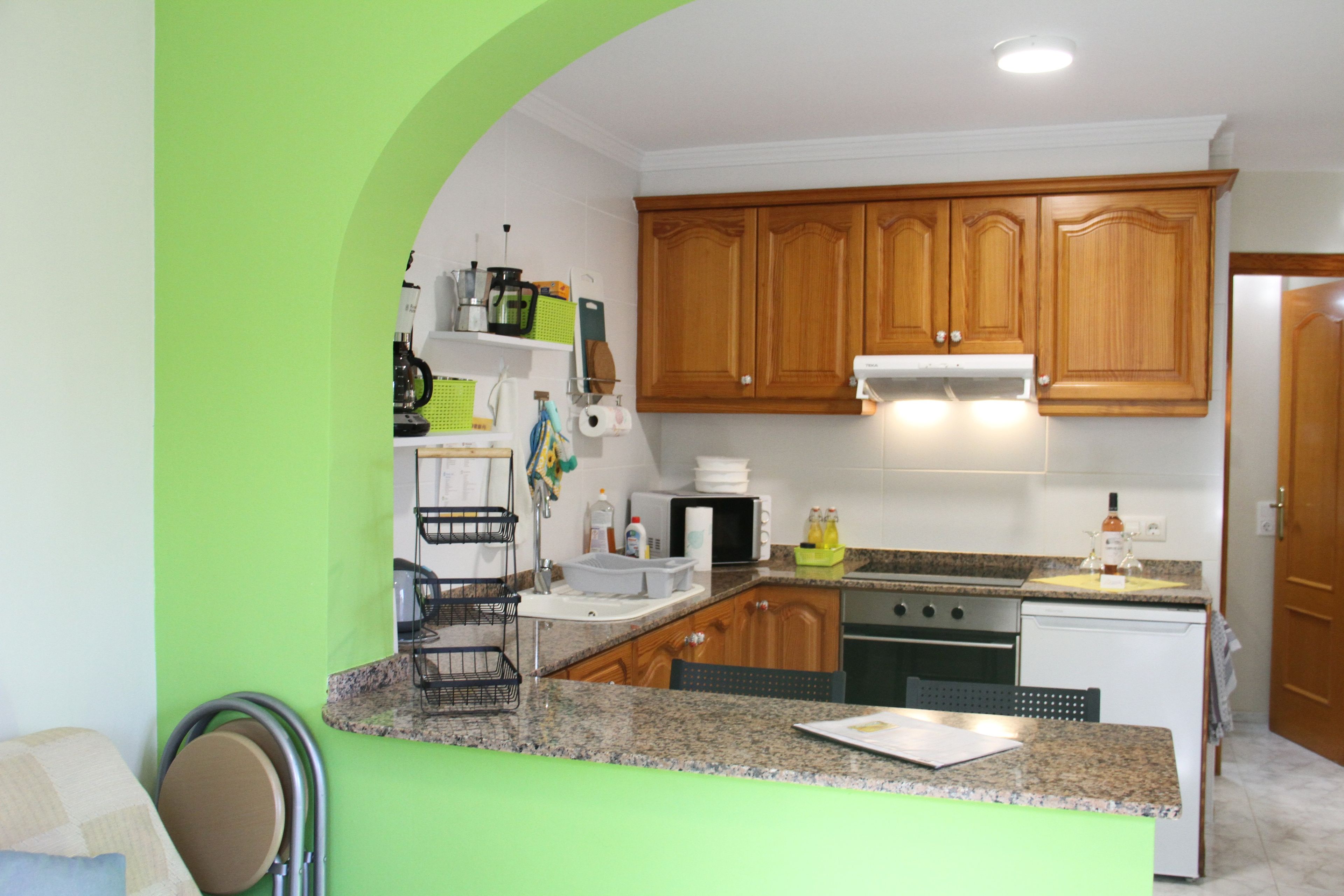 A kitchen with wooden cabinets, a granite countertop, and a stainless steel range hood.