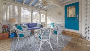 Ein gemütliches Zimmer mit blauer Tür, weißem Korbmöbel und einem Teppich mit Muster. Ein Deckenventilator ist ebenfalls vorhanden.