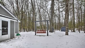 A snow-covered yard with a bench, a shed, and a house. - Remote Michigan Retreat on 10 Acres w/ Grill! (Wellston)