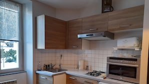 Une cuisine compacte avec des meubles en bois, une cuisinière à gaz, un four encastré et un petit réfrigérateur.