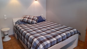Une chambre à coucher avec un lit, deux lampes fixées au mur, des toilettes blanches et un petit lavabo.