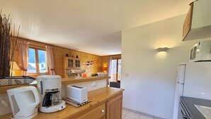 A compact kitchen with wooden cabinets, a countertop, a microwave, a toaster, and a coffee maker. - Spacious 3-Room Apartment in Praz-Sur-Arly, Sleeps 6, Central Location, Parking Included (Praz-sur-Arly)