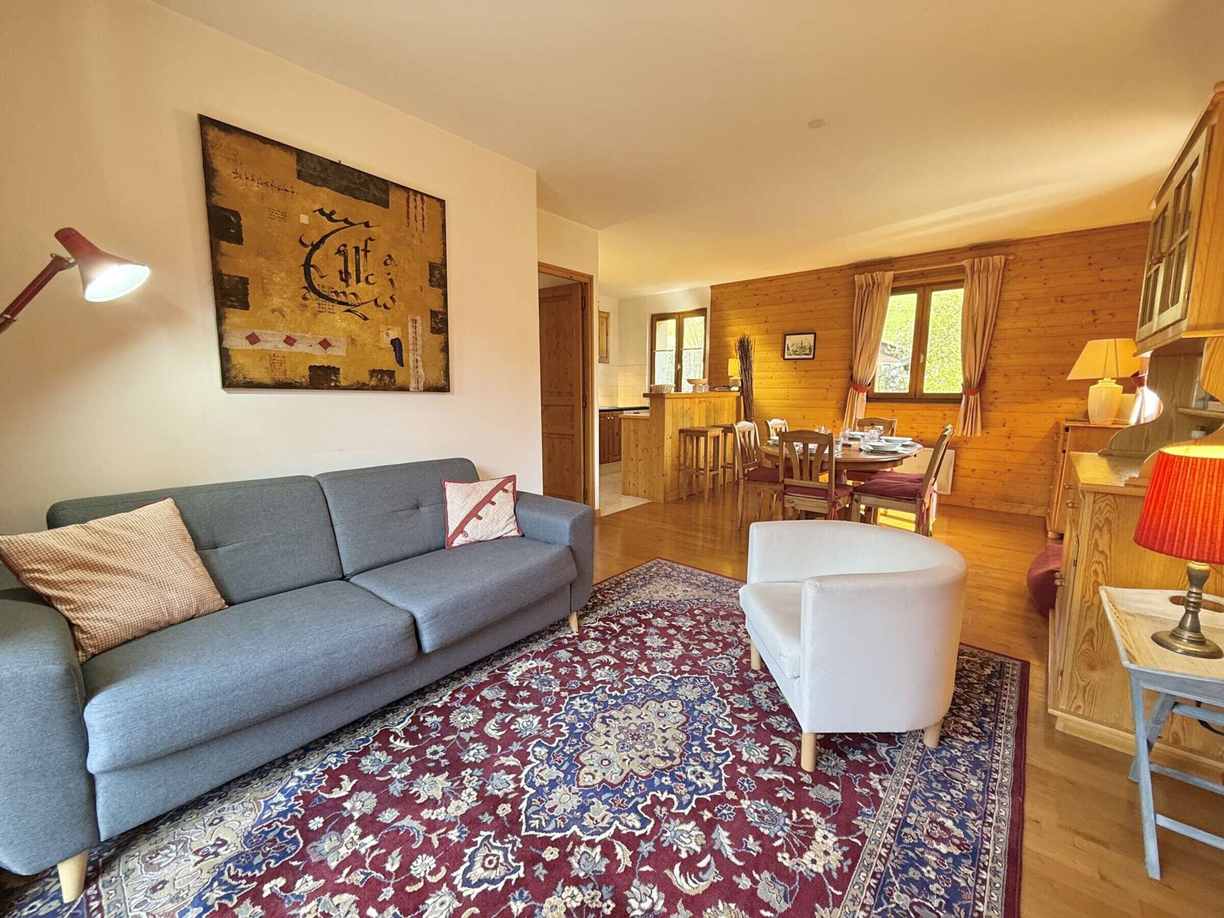 A modern living room with a grey sofa, a white ottoman, and a patterned rug.